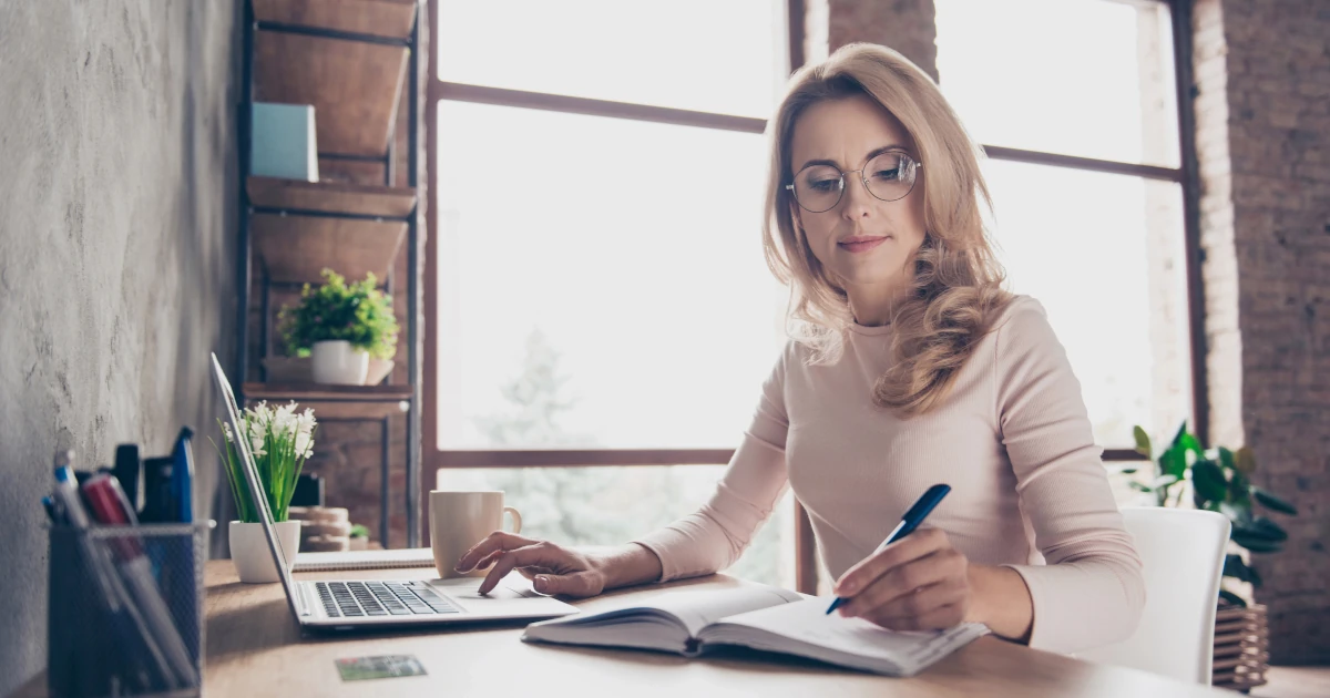 Femme étudiant sur ordinateur dans le cadre d'un apprentissage en ligne asynchrone, avec accès aux ressources éducatives pour une formation flexible et personnalisée.